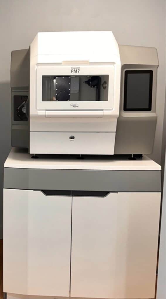 Fraiseuse PrograMill PM7 Ivoclar Digital sur son meuble de support en laboratoire dentaire.